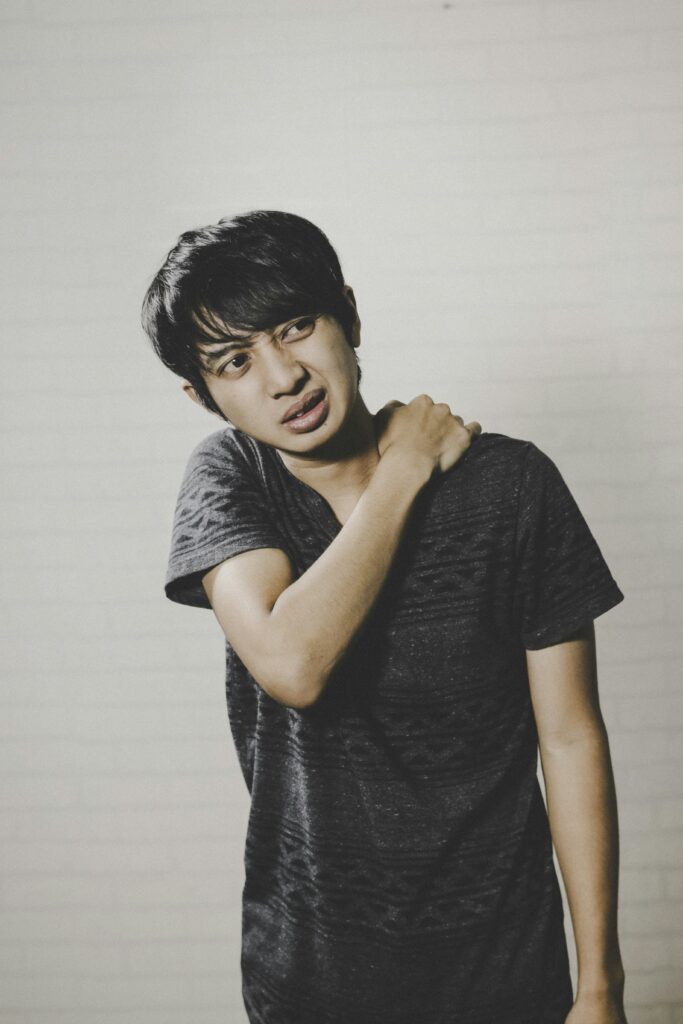 persoon met schouderpijn bij schouderblessure waarbij een schouderbrace ondersteuning kan geven